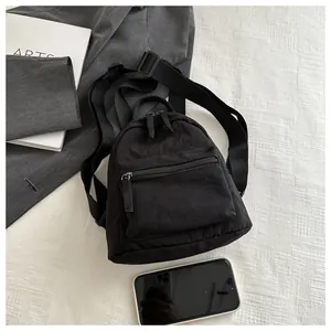 Mini black canvas backpack shown next to a smartphone for size scale and detail