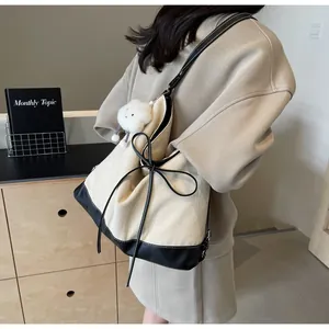 Detail of herringbone canvas tote bag with black leather trim and bow decoration
