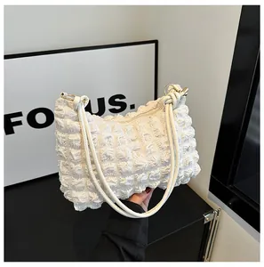 Detail of white bubble texture fabric with thin shoulder strap and metal ring on handbag