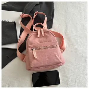 Detailed close-up of a pink mini nylon backpack next to a smartphone for size reference