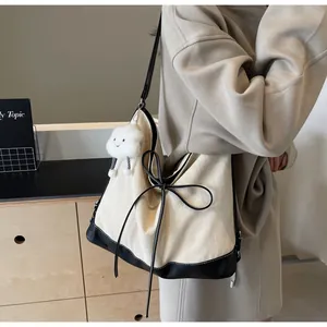 Detail view of cream herringbone tote bag featuring black leather trim and bow knot