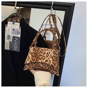 Detail shot of leopard print handbag with curved base and adjustable shoulder strap