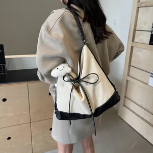 Large cream canvas tote bag with black leather trim and bow detail shown on shoulder
