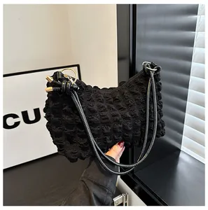Detail of black bubble texture shoulder bag with gold ring hardware and sleek straps