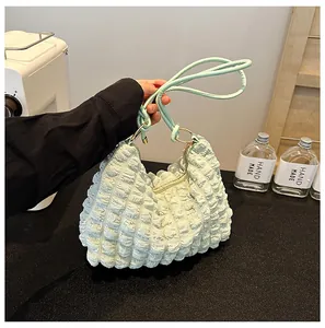 Detail of light green bubble pleated fabric and thin shoulder straps on a tote bag