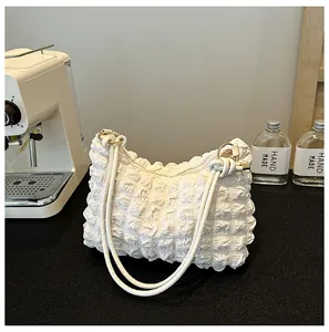 Detailed close-up of white bubble textured handbag with slim straps and golden hardware