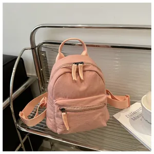 Detail of pink mini canvas backpack on silver shelf with texture and zipper focus