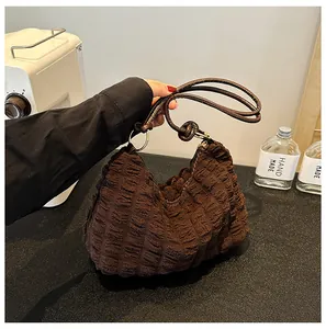 Detail view of the textured dark brown bubble pleat fabric and knot strap on this hobo bag