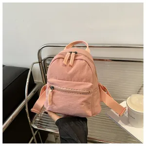Close-up of pink canvas mini backpack featuring double zip main pocket and front zip pouch