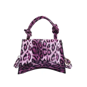 Purple leopard print handbag with knotted handle and curved base on a white background