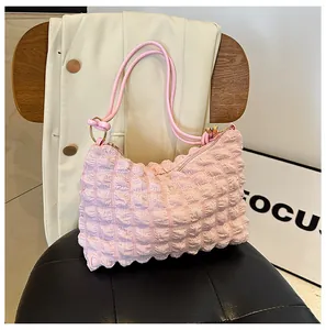 Close-up of pink popcorn fabric shoulder bag featuring soft textured bubble surface and gold rings