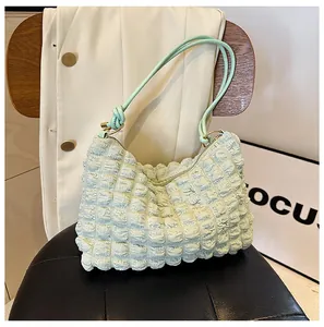 Detail of light green bubble textured shoulder bag with a stylish knot on the strap