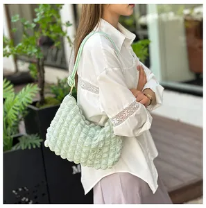 Macro detail of the light green pleated bubble texture fabric on a stylish shoulder bag