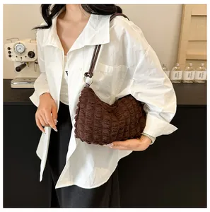 Detail of soft bubble textured dark brown shoulder bag with thin leather straps