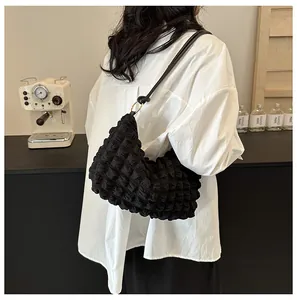 Detail of black bubble pleated shoulder bag with leather strap and golden metal hardware