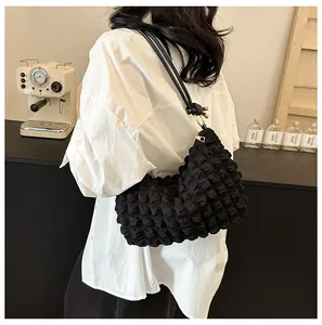 Detail showing 3D popcorn fabric texture and golden zipper of black shoulder bag