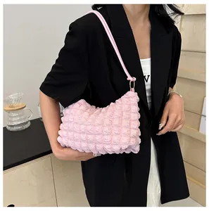 Close-up of a soft pink bubble textured shoulder bag worn by a model in a modern room