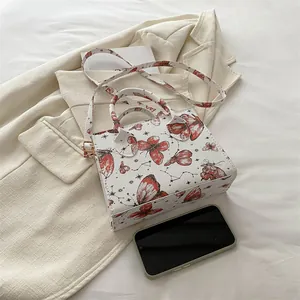 Square butterfly print handbag with red patterns and crossbody strap on blazer background