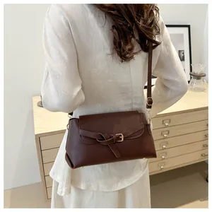 Sac bandoulière en cuir marron avec boucle vintage et nœud porté par le modèle