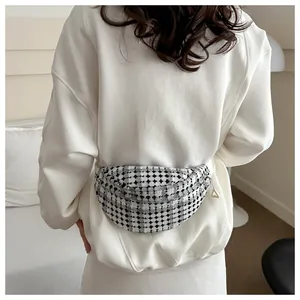 Close-up of black and white checkered tweed belt bag with metal zipper on a white sweatshirt