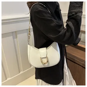 Detailed view of white leather crescent bag with golden D-clasp and chain strap worn by model