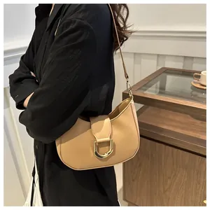 Detail of camel hobo bag showing golden horseshoe buckle and leather strap on model