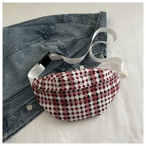 Detail of red and black plaid waist bag with white nylon strap on denim jacket