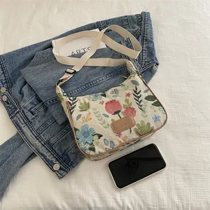 Floral jacquard crossbody bag with red floral pattern and wide strap on denim jacket