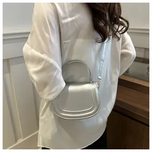 Dettaglio di una borsa a sella argento metallizzato con cuciture a vista su modella
