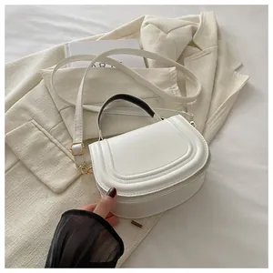 Dettaglio di borsa a sella bianca in pelle con eleganti motivi a cerchi goffrati