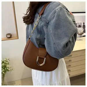 Detail of dark brown dumpling bag featuring gold horseshoe buckle and chain strap