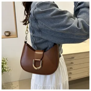 Close-up of brown crescent bag with gold horseshoe buckle on model with denim jacket