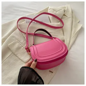 Dettaglio della borsa a sella rosa in ecopelle con tracolla su un blazer crema