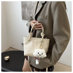 Chic beige bucket bag with knot handle and a cute cloud plush charm on a blazer outfit