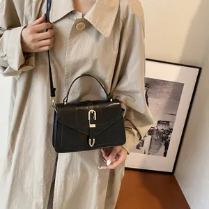 Fashionable black leather crossbody bag with golden U-shaped clasp shown on a model