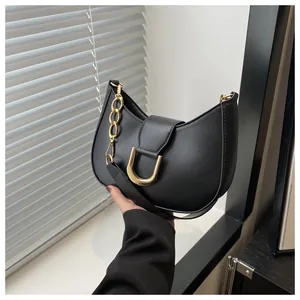 Close-up of black half-moon bag featuring a gold horseshoe buckle and elegant chain strap