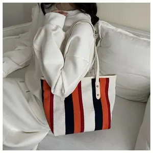 Close-up of vibrant striped canvas tote bag with metal rivet reinforcement details