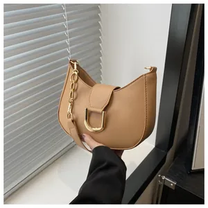 Detail view of light brown crescent bag featuring gold U-shaped buckle and chunky chain