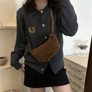Brown suede croissant shoulder bag with pleated design worn by a model in interior setting