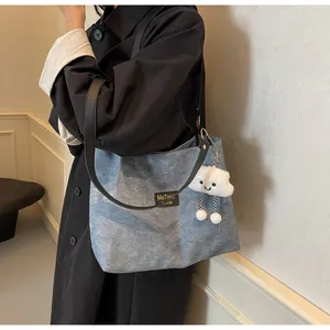 Détail du sac fourre-tout en toile denim bleue avec lanières en cuir noir et nuage