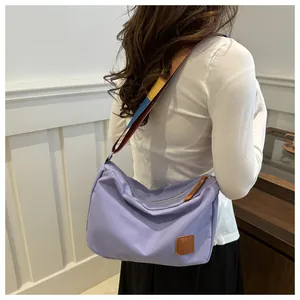 Détail du sac en toile lilas avec bandoulière tissée colorée et logo en cuir premium