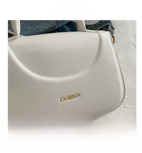 Dettaglio della borsa in pelle bianco crema con scritta Fashion dorata e patta