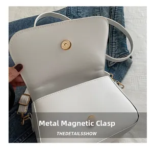 Dettaglio della chiusura magnetica dorata su una borsa a tracolla in pelle PU bianca