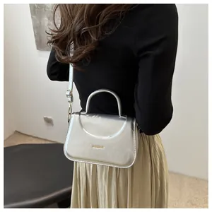 Dettaglio della borsa metallizzata argento con scritta FASHION e tracolla sottile