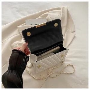 Macro detail of white quilted crossbody bag showing interior space and golden magnetic clasp