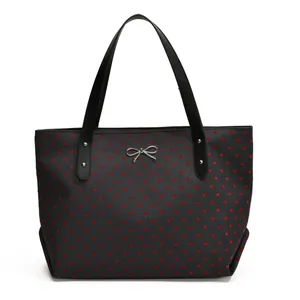 Bolso tote negro con corazones rojos y un lazo metálico plateado en la parte frontal
