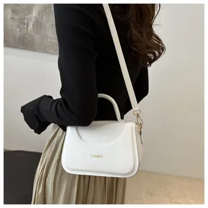 Dettaglio laterale della borsa a tracolla in finta pelle bianca con scritta FASHION oro