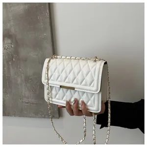 Detail shot of white quilted flap crossbody bag with gold metal chain and leather strap