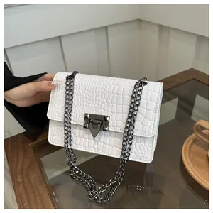 Détail du sac blanc à motif crocodile avec bandoulière en chaîne et fermoir à clous pyramide