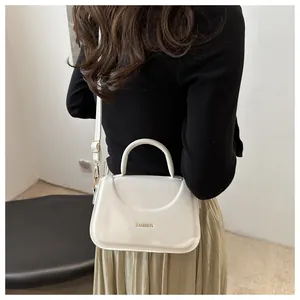 Dettaglio borsa a mano bianca con scritta Fashion dorata e tracolla regolabile